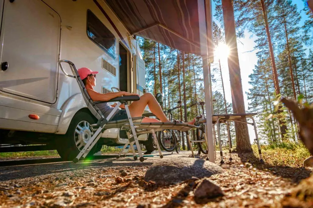 a woman seated in a reclining chair under the campervan awning