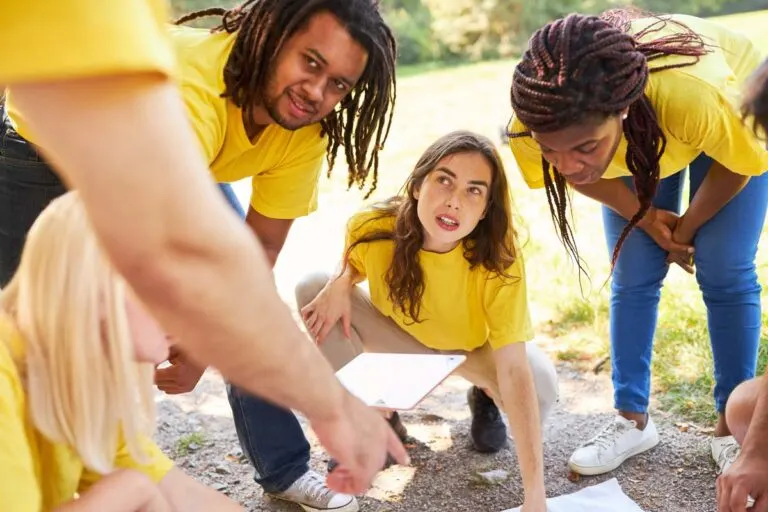 Team in matching yellow shirts gathered around a scavenger hunt list outdoors