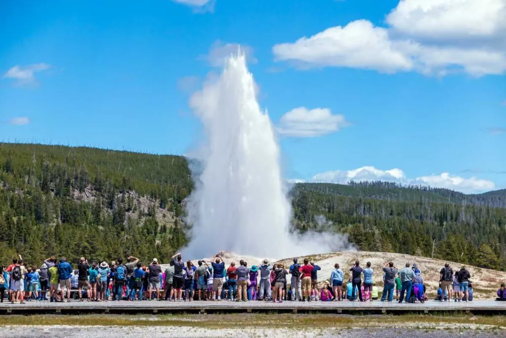 A crowd of tourists watching the Old Faithful Geyser erupting