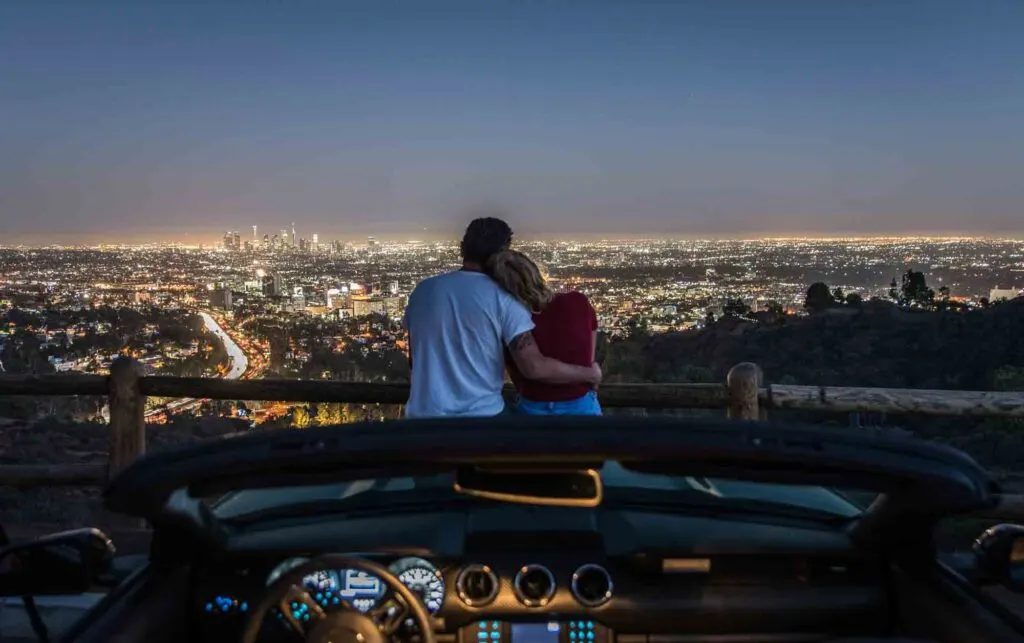 Couple enjoying skyline view from their car in the night