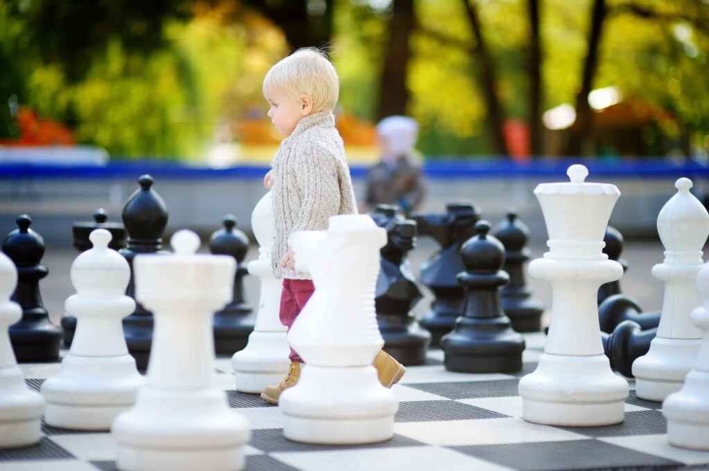 Toddler boy playing giant chess outdoors