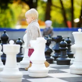 Toddler boy playing giant chess outdoors